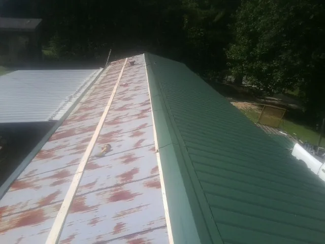 Old rusted panels beside newly installed green metal roofing — Wind Damage Roof Repair by Roofing Brothers in Secaucus