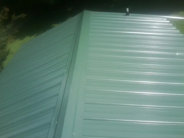 New green metal panels meeting at the ridge of a roof — Flat Roof Repair work by our crew in Secaucus