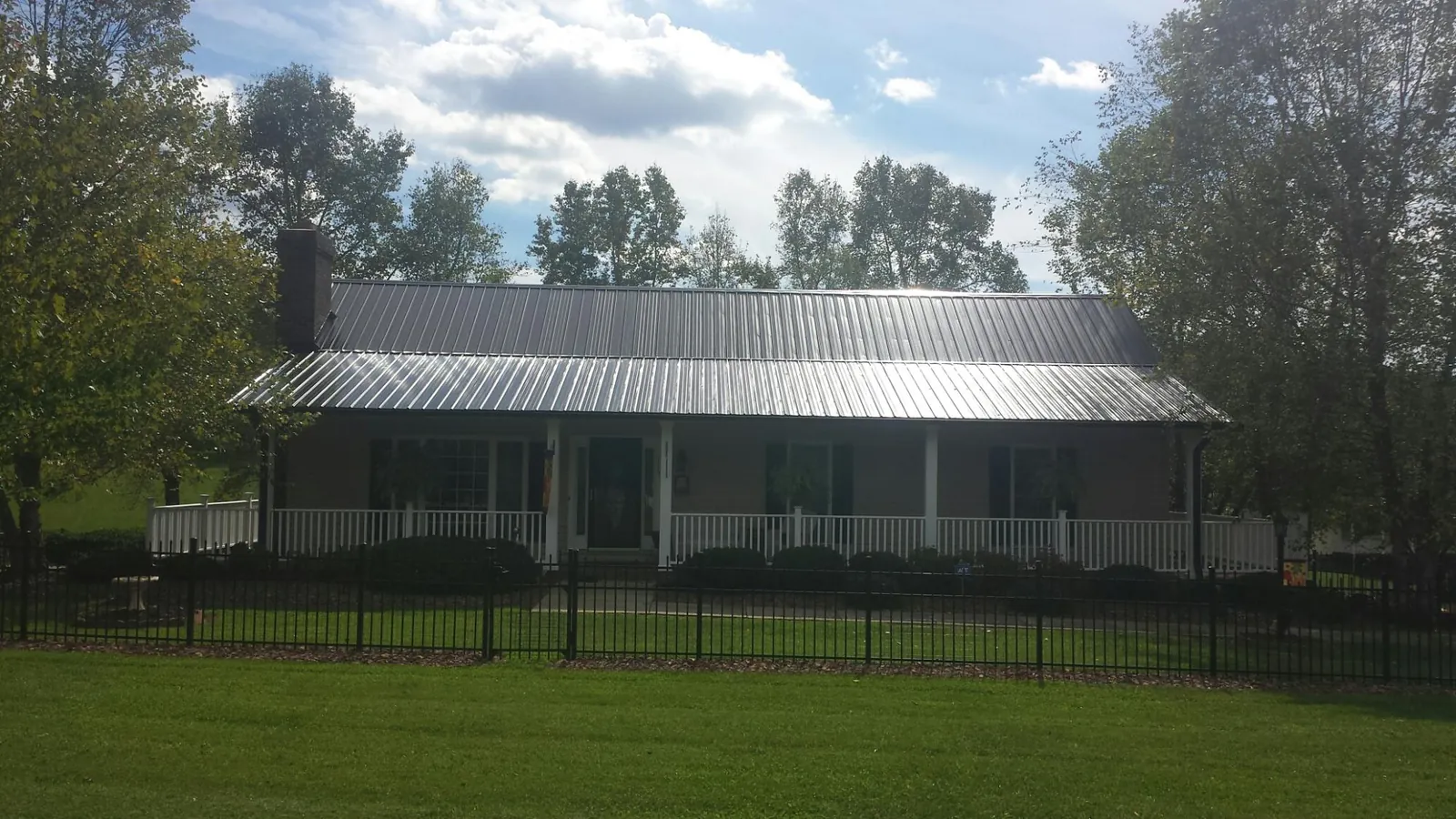 Gray metal roof on a brick ranch with a full width front porch — Gutter Guard Installation work by our crew in Secaucus