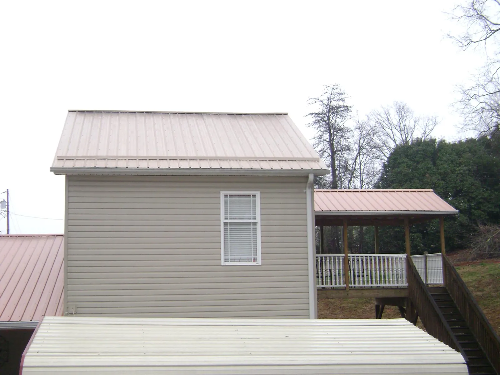 Tan metal roofs on a two story addition and attached porch, from a Roof Replacement job in Secaucus