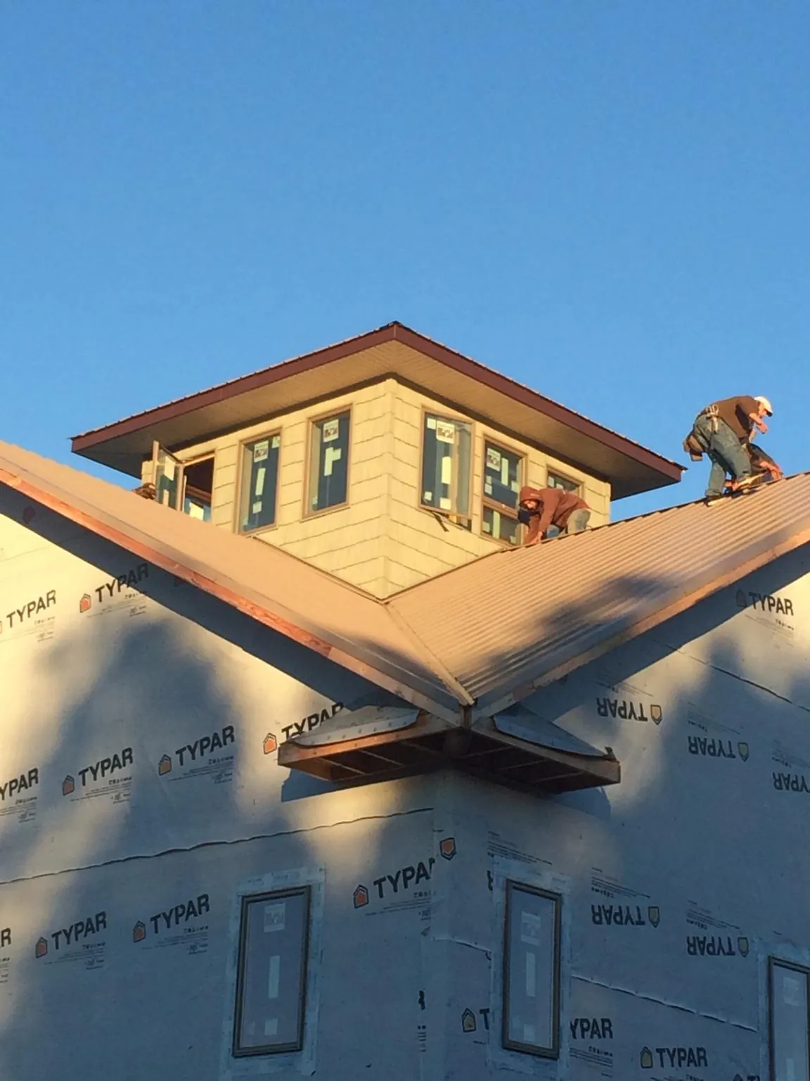 Roofers working around a rooftop cupola on a new metal roof at sunset — Roof Waterproofing in Secaucus by Roofing Brothers